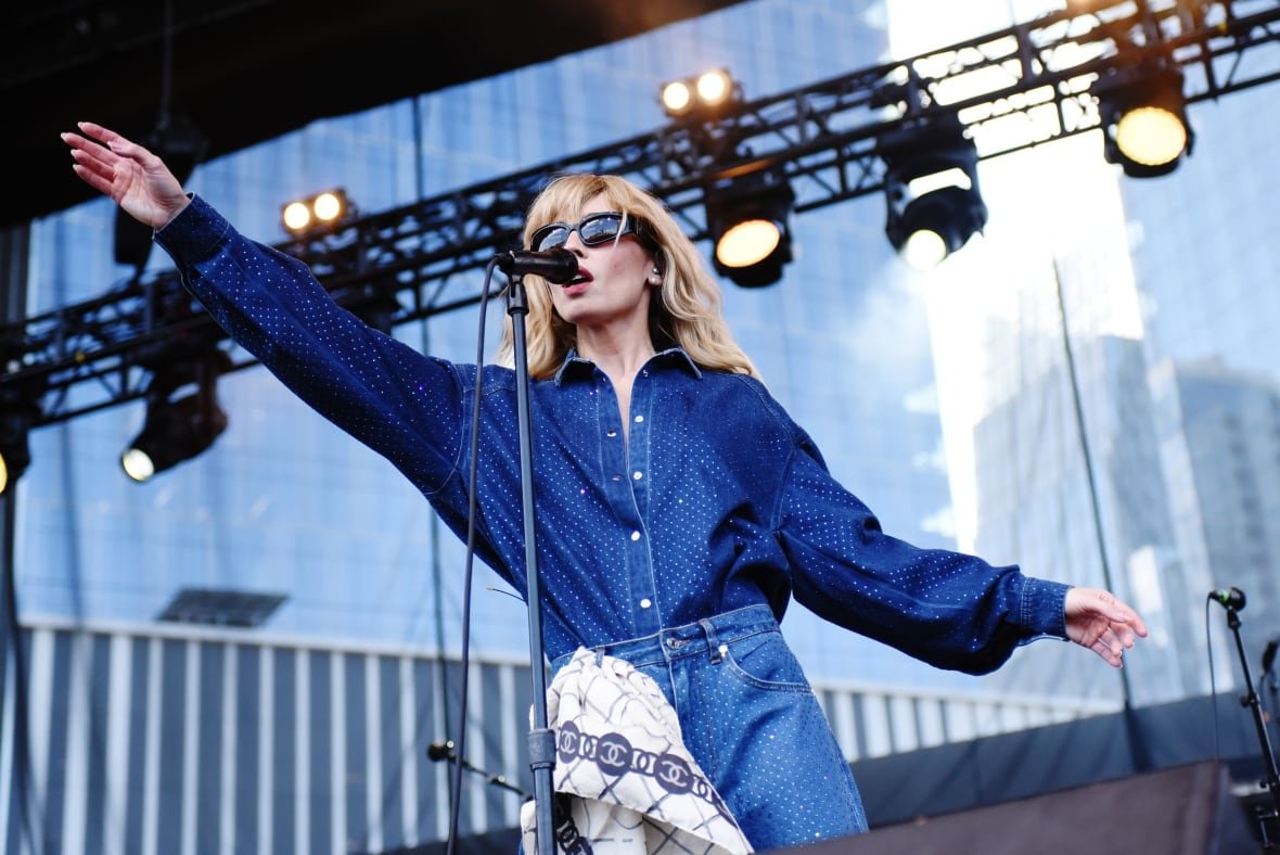 A blond singer is show on stage wearing blue.