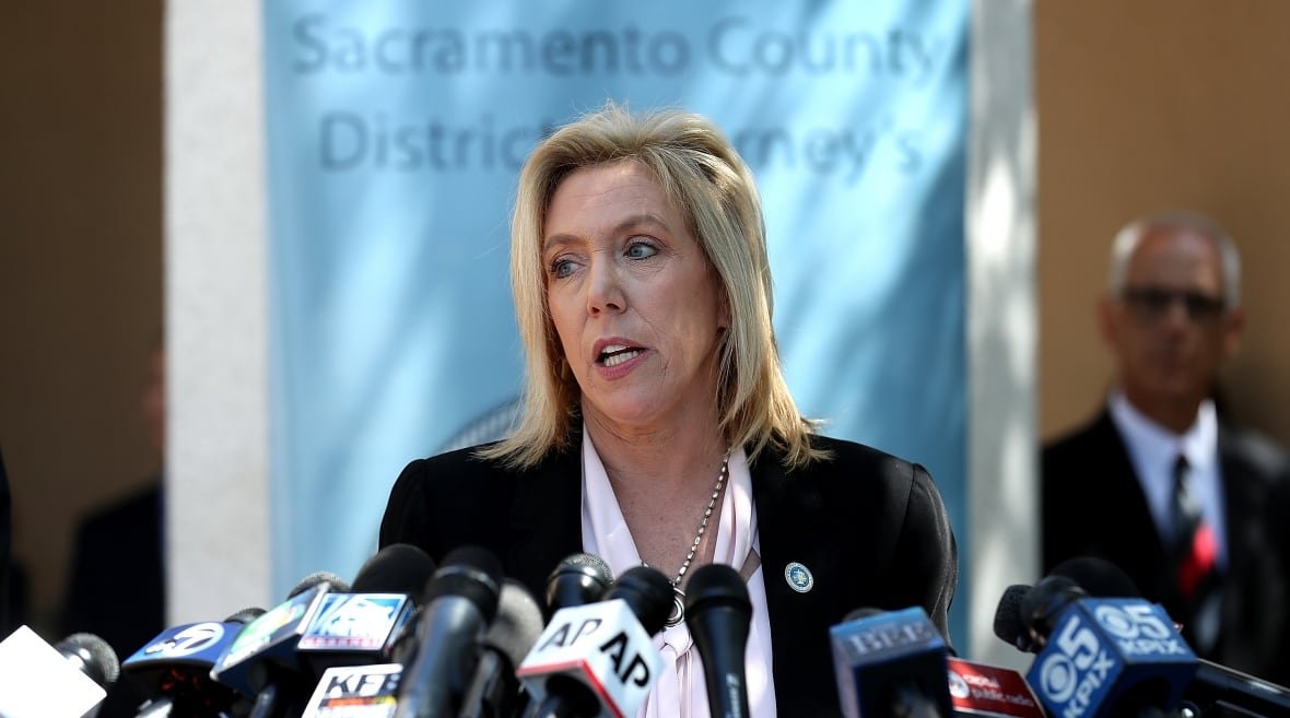 99900721 A woman stands at a podium answering questions.
