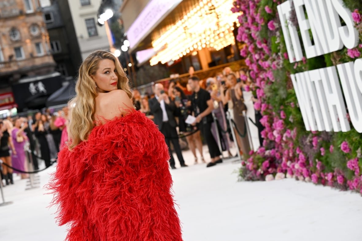 blake-lively-it-ends-with-us A person in a courtyard at a movie premiere looks back toward the camera.