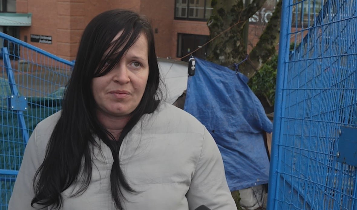 jenny-robbins-abbotsford-tent-encampment-november-2024 An unhappy woman with a sad face in a grey, insulated jacket with dark hair speaks to a reporter.