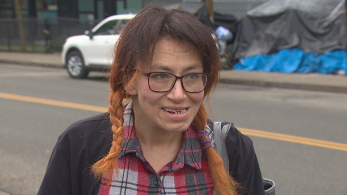 kimberlee-kirton-coquitlam-shelter A woman in a plaid shirt and wearing glasses speaks with a reporter.
