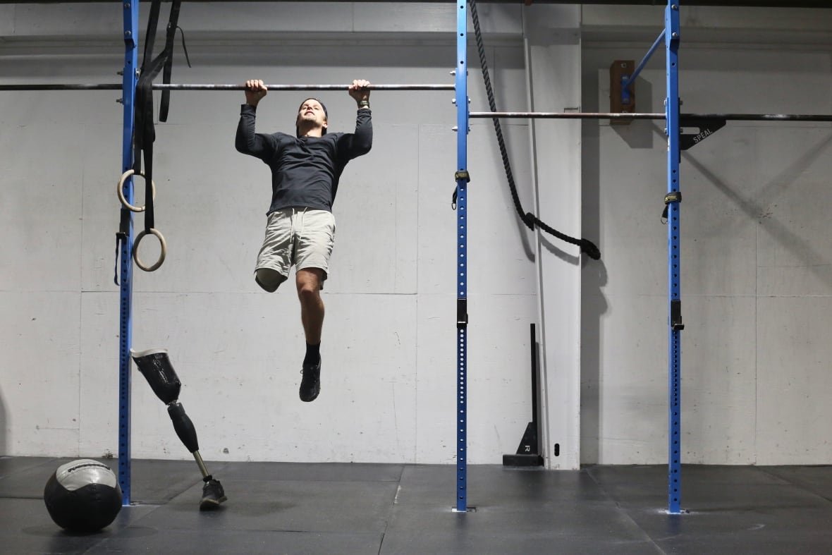 lucas-arsenault-1 A man with one leg does a pull up at a gym.