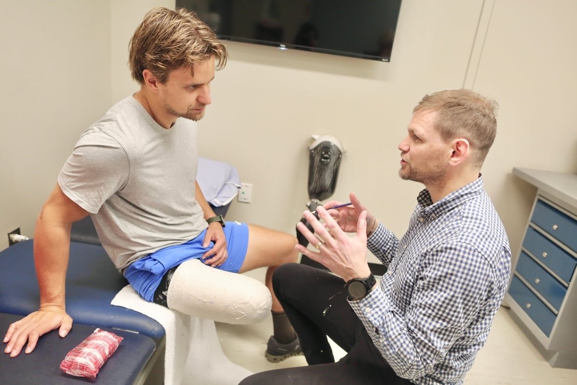 lucas-arsenault-and-todd-waite A man with a leg speaks with health care provider.