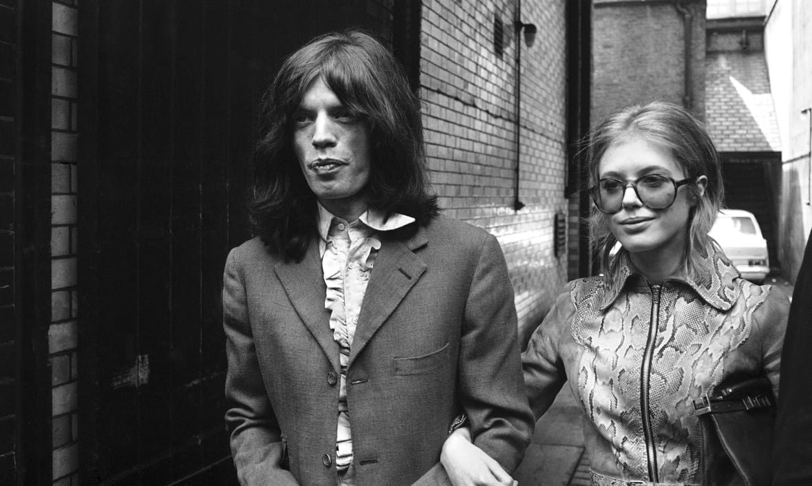 marianne-faithfull-obit-1 A man and a woman walk arm in arm in this black and white photo.