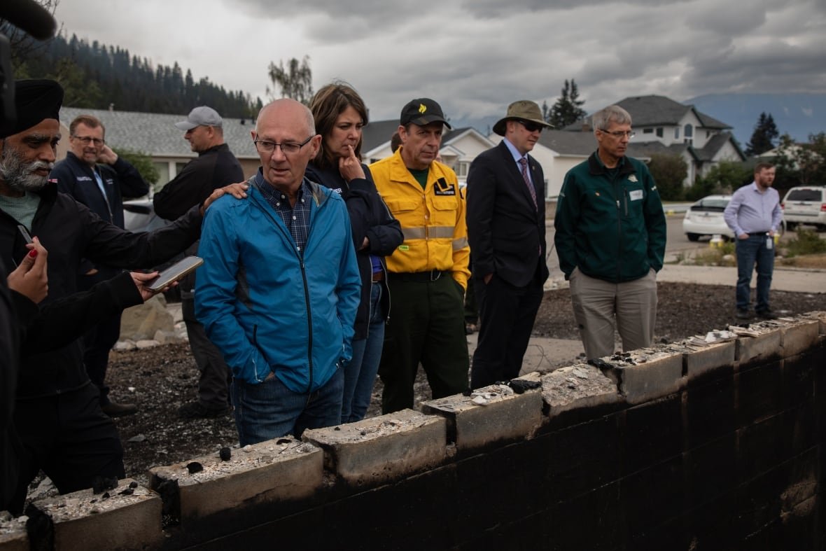 A group of people look over the foundation of a burned home.