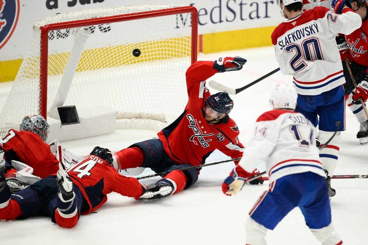 canadiens-capitals-hockey-1 Players sprawling on the ice in front of a net.