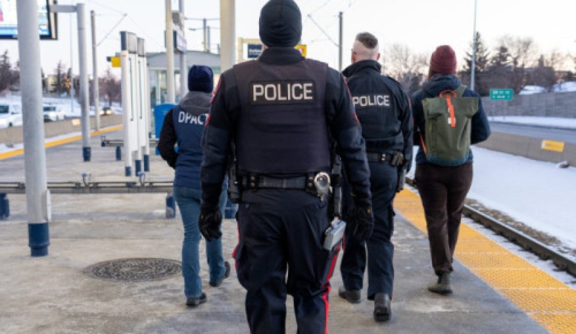 cps-ctrain-1 Two police officers and two outreach workers walk away from the camera on a CTrain station platform.