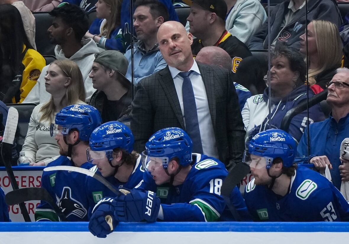 hkn-golden-knights-canucks-20250416-1 Hockey coach stands behind players behind the bench.