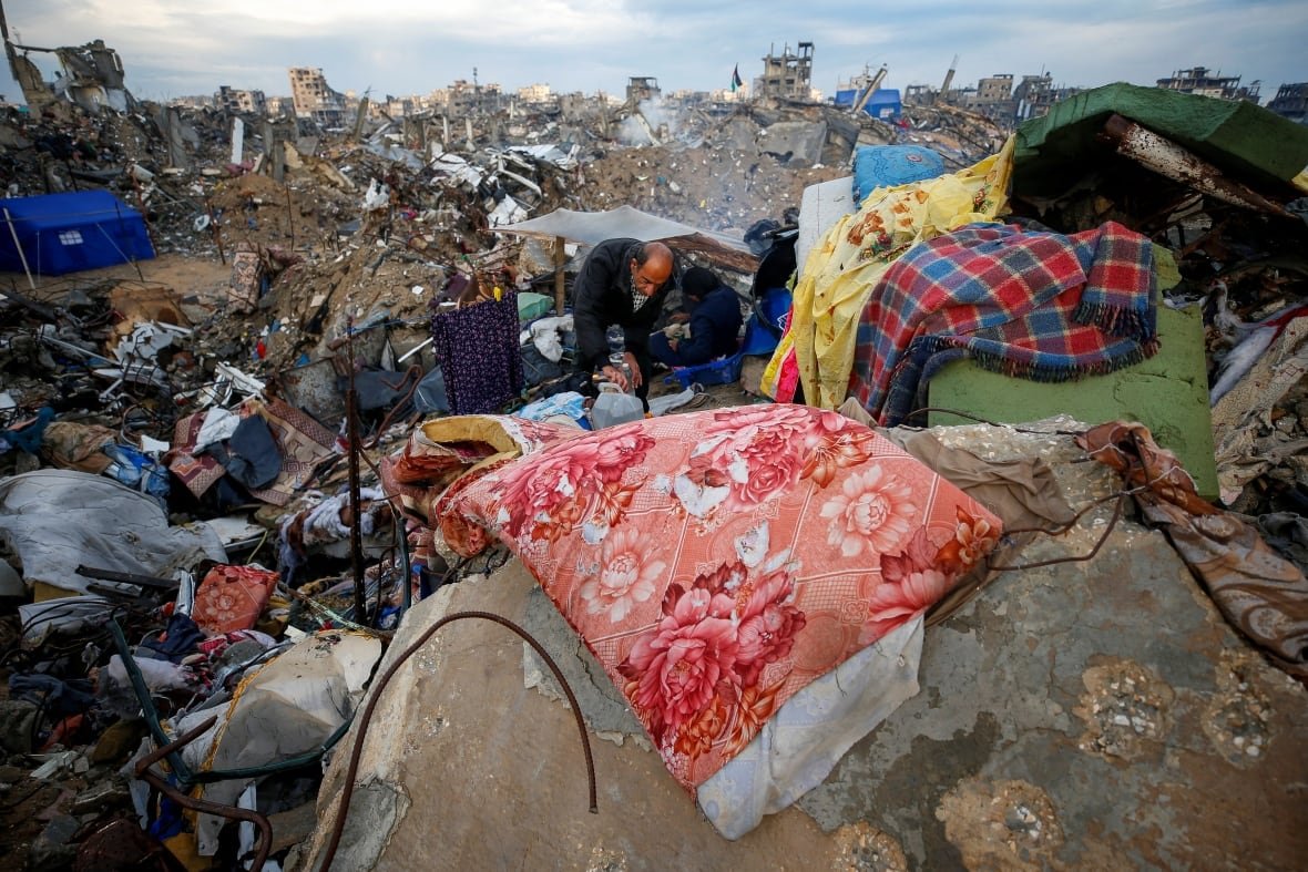 israel-palestinians-gaza-ceasefire-trump-1 A man collects water from atop rubble.