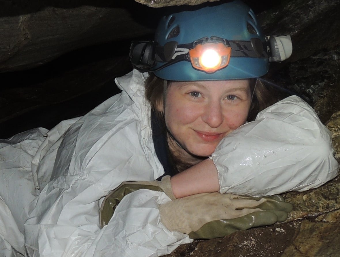 karen-vanderwolf-1 A woman with a helmet with a light on it lying inside a cave
