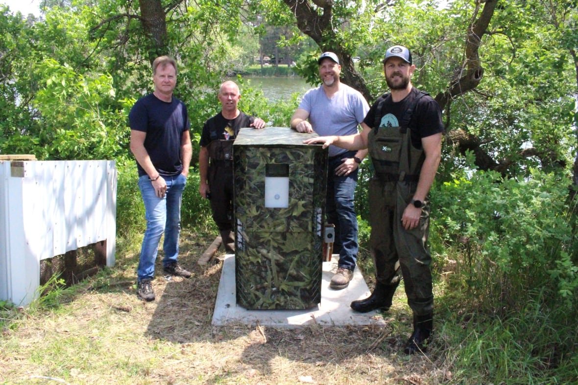 killarney-lake-1 Four men stand by a large camo colour box.