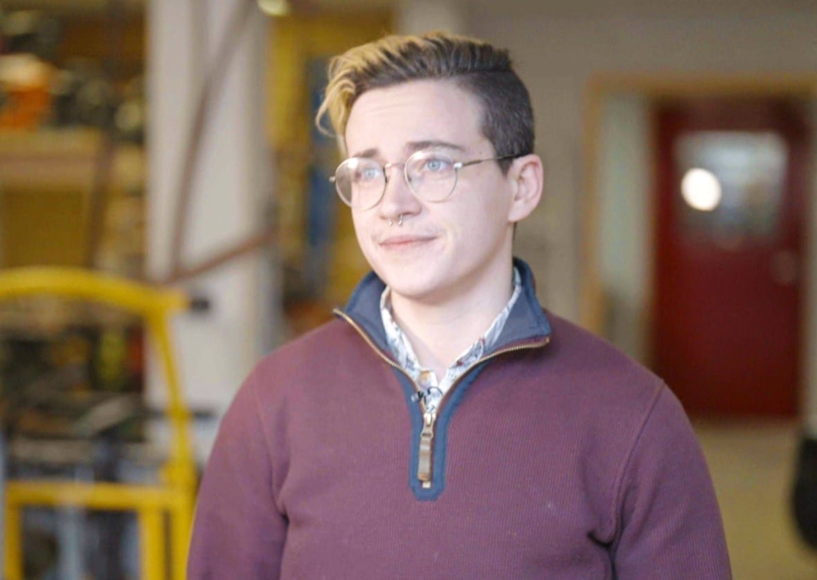 mariah-darling Person with short blond hair wearing burgundy sweater, and glasses looking at camera.