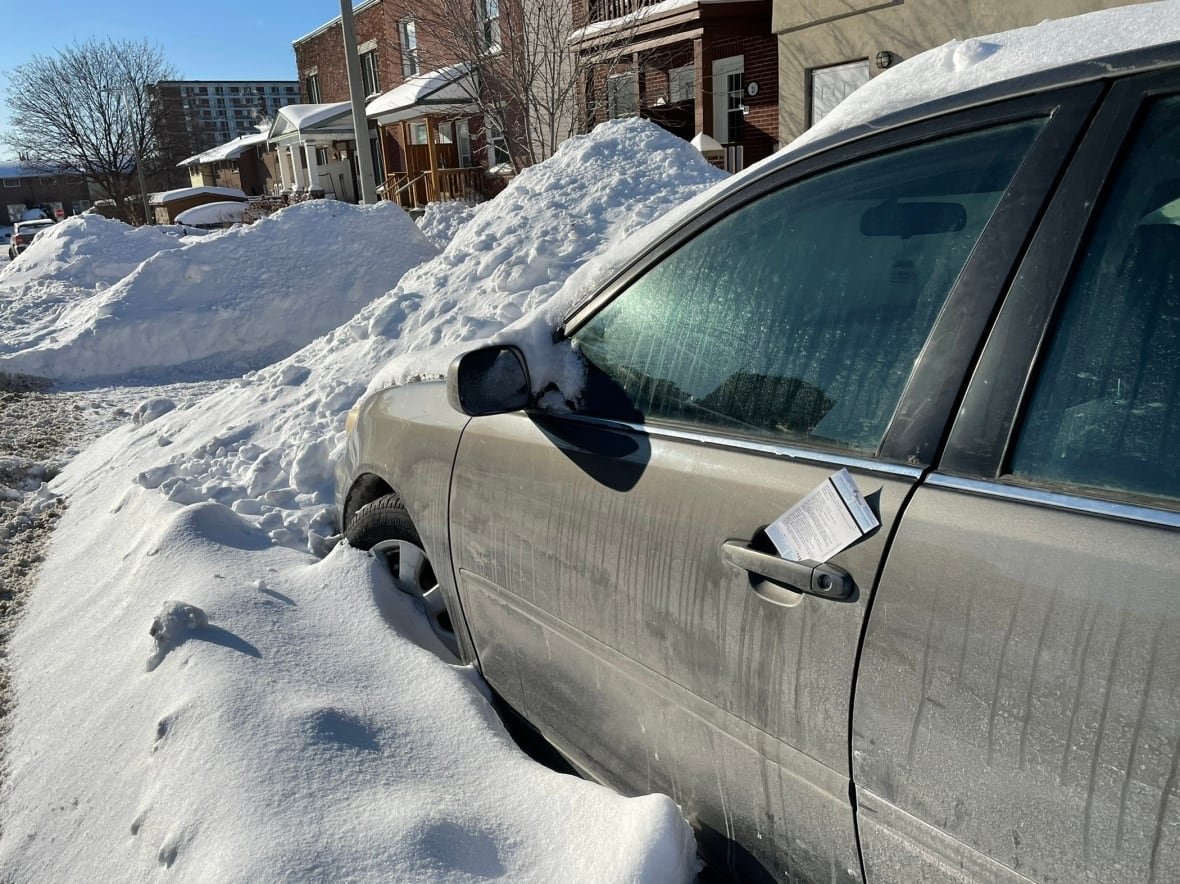 parking-ban-ticket-winter-ottawa A parked car on a city street in winter. There's a parking ticket stuck in its door.
