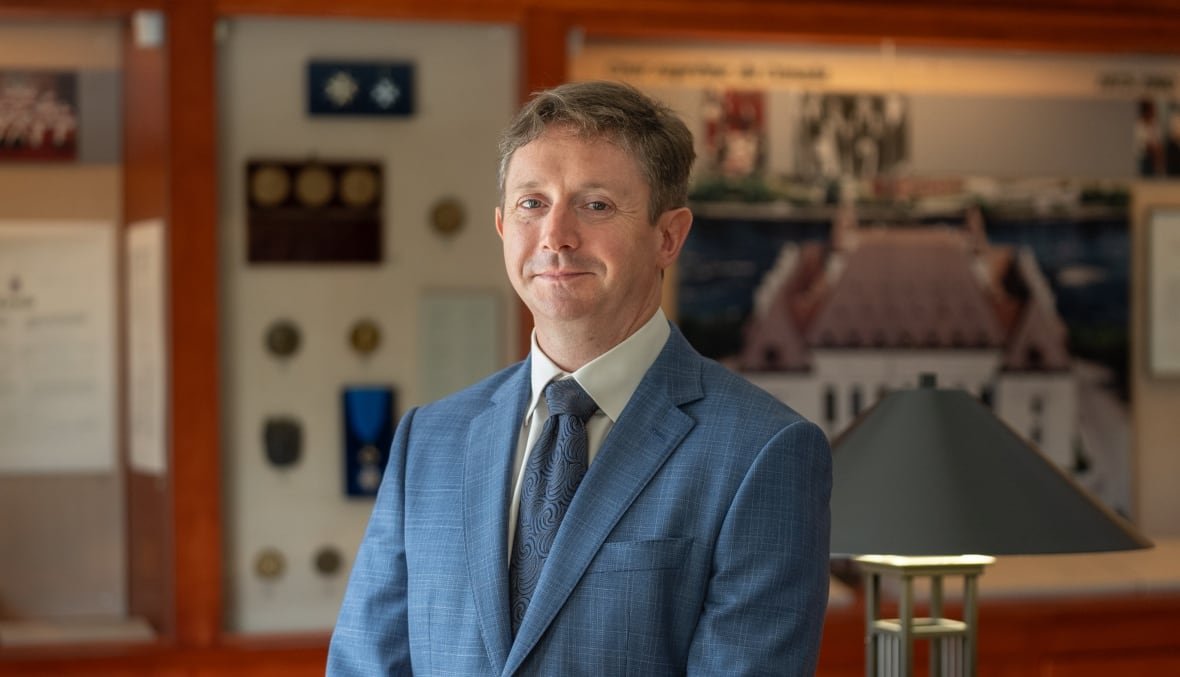 paul-daly Man standing in an office, smirking, looking at camera.