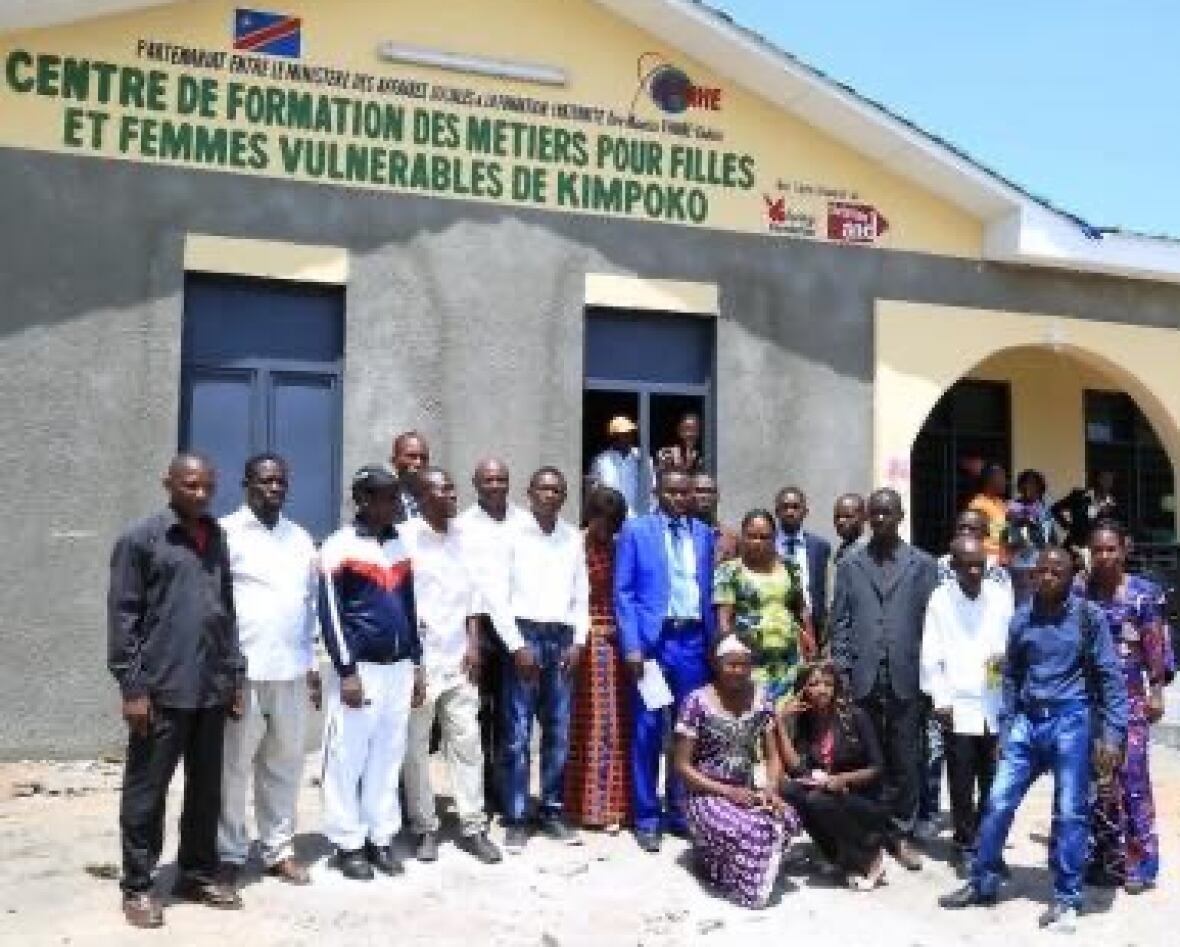 school-in-congo More than a dozen people stand in front of a school in Kimpoko.
