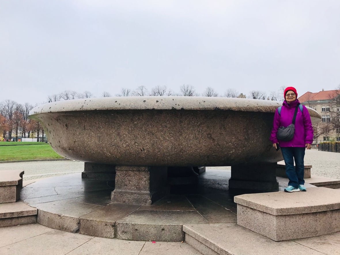 siok-har-lim Woman in fuchsia jacket standing beside monument, smiling.
