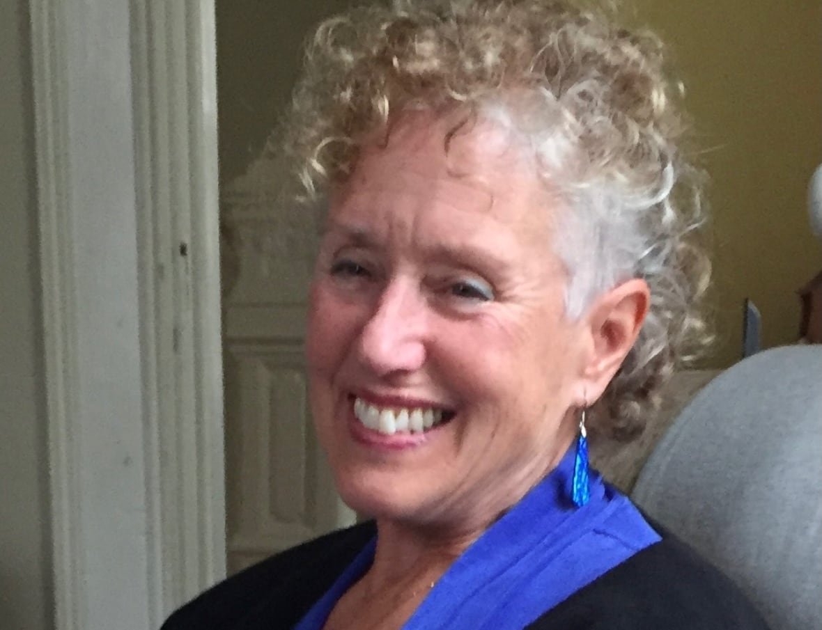 A woman smiles, looking off camera.