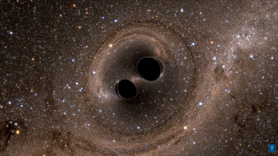 two-black-holes-merge-into-one Two black holes are shown next to each other over a brownish black backdrop of space.