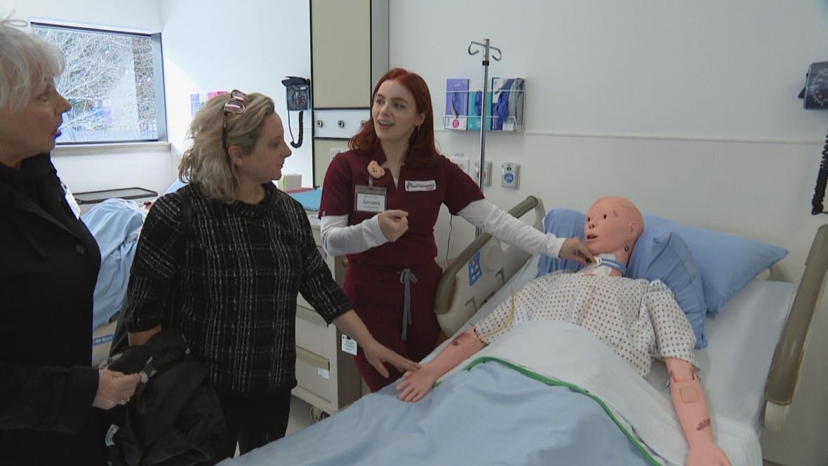 beal-university-lab-sackville A woman in scurbs next to a medical dummy. Two people in plain clothes watching her.
