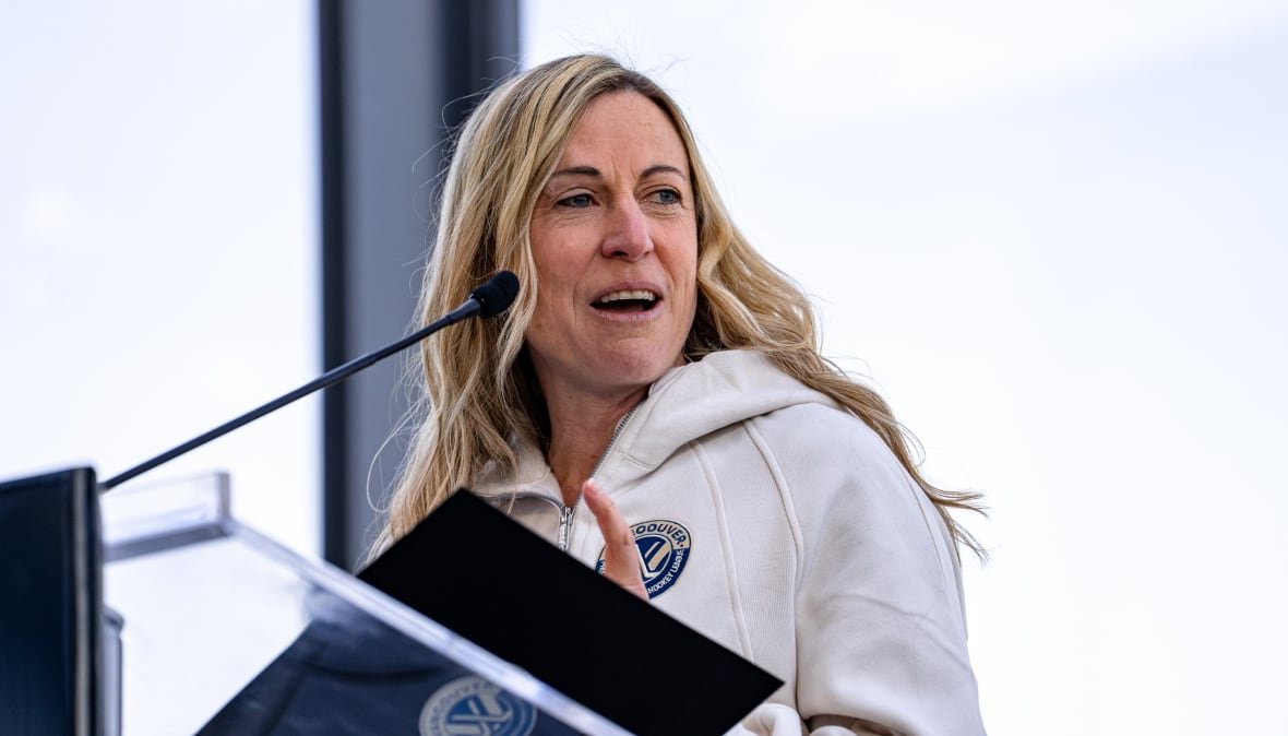 jayna-hefford-pwhl-vancouver-expansion A woman wearing a white sweater, with a PWHL Vancouver logo on it, speaks at a podium.