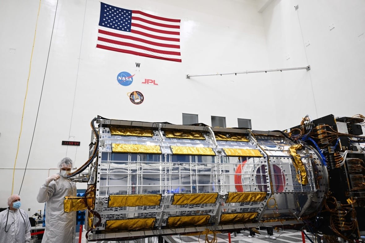 Someone works on a satellite in a lab.