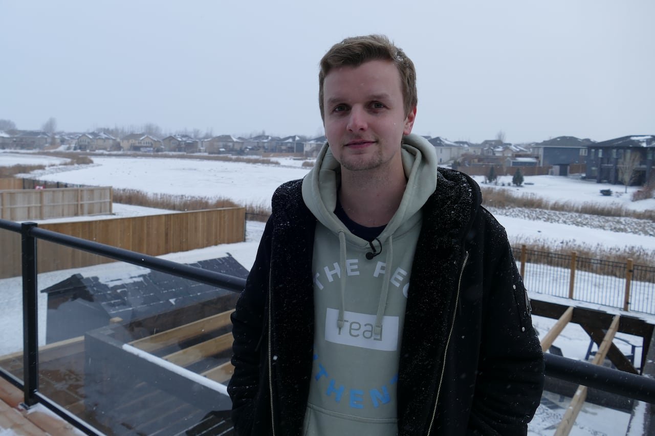 A man stands on his deck with a retention pond in the background.