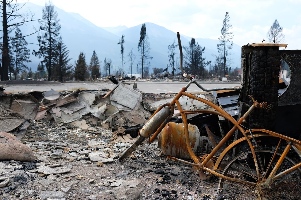 A burned-out bicycle is seen among charred debris in a town.