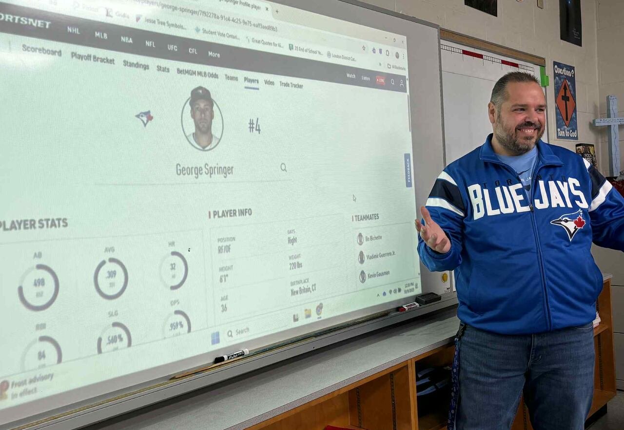 A man stands at a board with baseball player stats on it