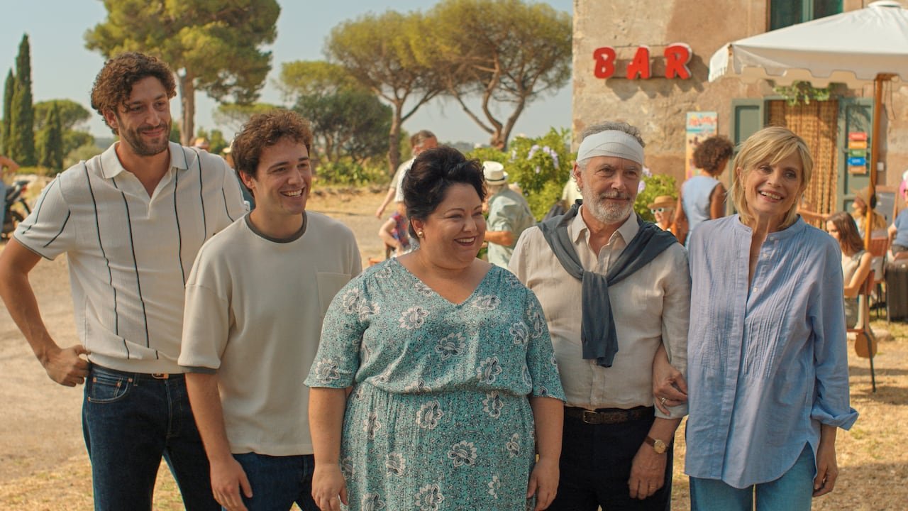 A group of smiling people stand outside.