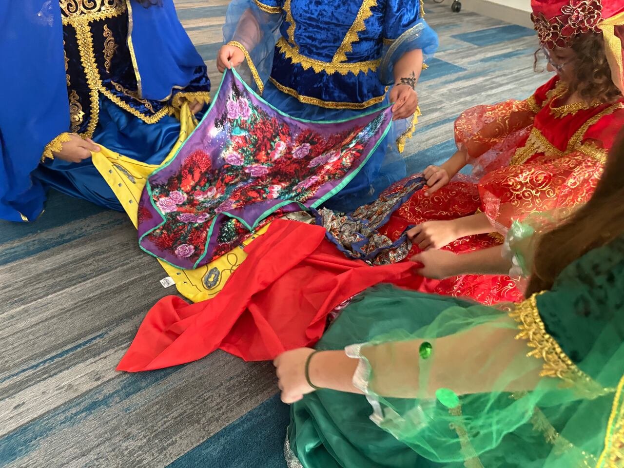 Hands holding colorful fabric scarves above the ground.