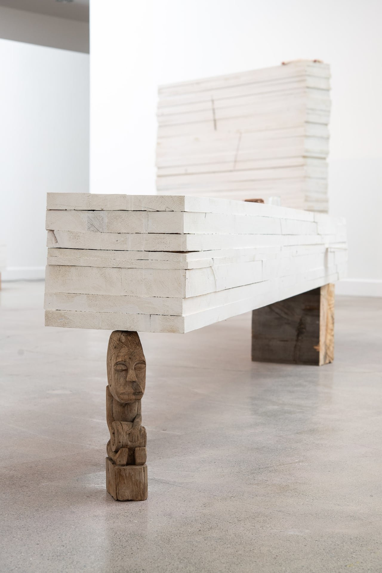Artwork showing grey flat material balanced on a small carved sculpture.