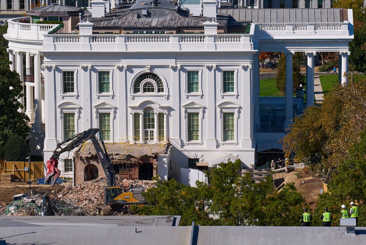 Construction workers, atop the U.S. Treasury at bottom right, watch as demolition continues on the White House's East Wing in October to make room for a new ballroom.