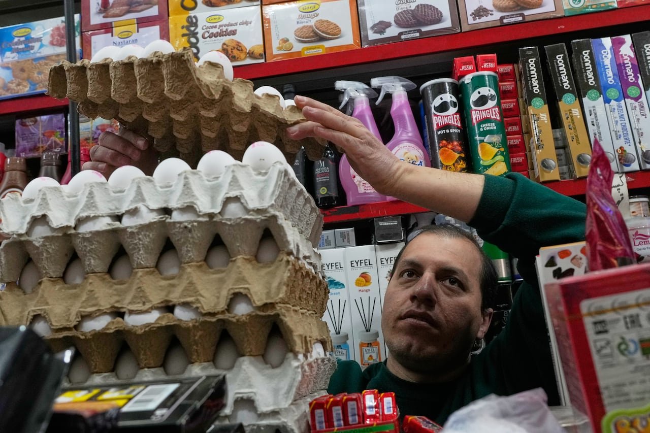 default-9363 A man stands in front of a display of grocery items and arranges crates of eggs