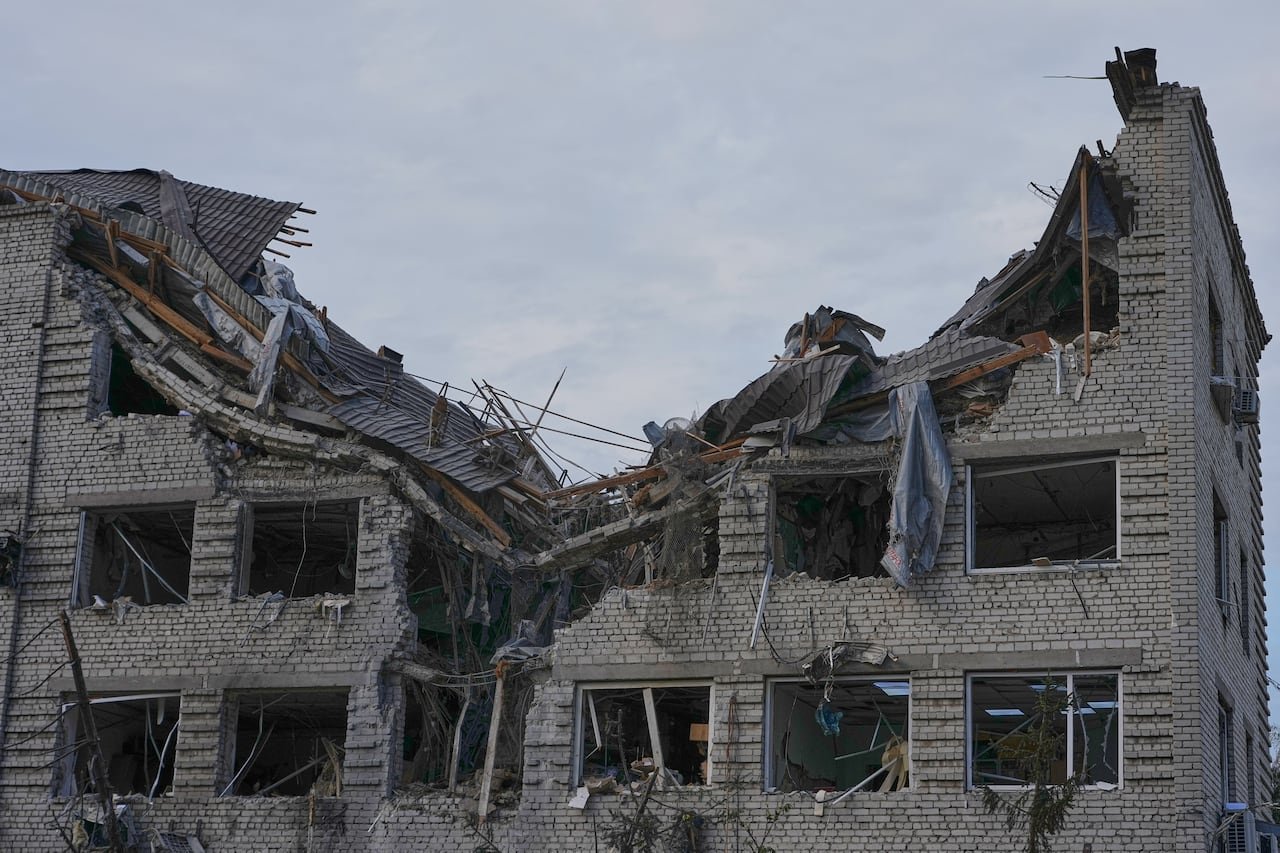 A multi-level brick building is shown with the roof caved in and all the windows blown out.